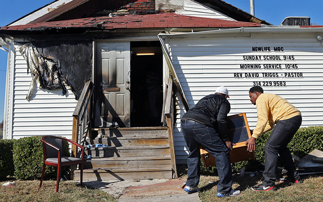 Deacon Clinton McMiller (left) and Pastor David Triggs carry a cabinet back into New Life Missionary Baptist Church in St. Louis on Oct. 18. An outdoor service had been held there because of a fire at the church that was believed to be intentionally set. (J.B. Forbes/St. Louis Post-Dispatch via AP)