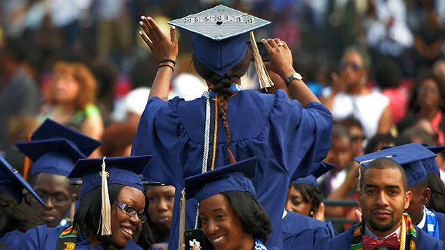 A graduate waves to family members as she takes her seat for Howard University's commencement in May 2014. (Bill O'Leary/The Washington Post via Getty Images)